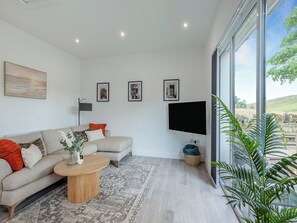 Una sala de estar moderna con un sofá, una mesa de centro, un televisor de pantalla plana y cuadros enmarcados en la pared.