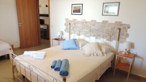 A neatly made bed with rolled towels, a stone-patterned headboard, and two bedside lamps. - Apartment with sunset view of the islands of Alicudi and Filicudi  (Pianoconte)