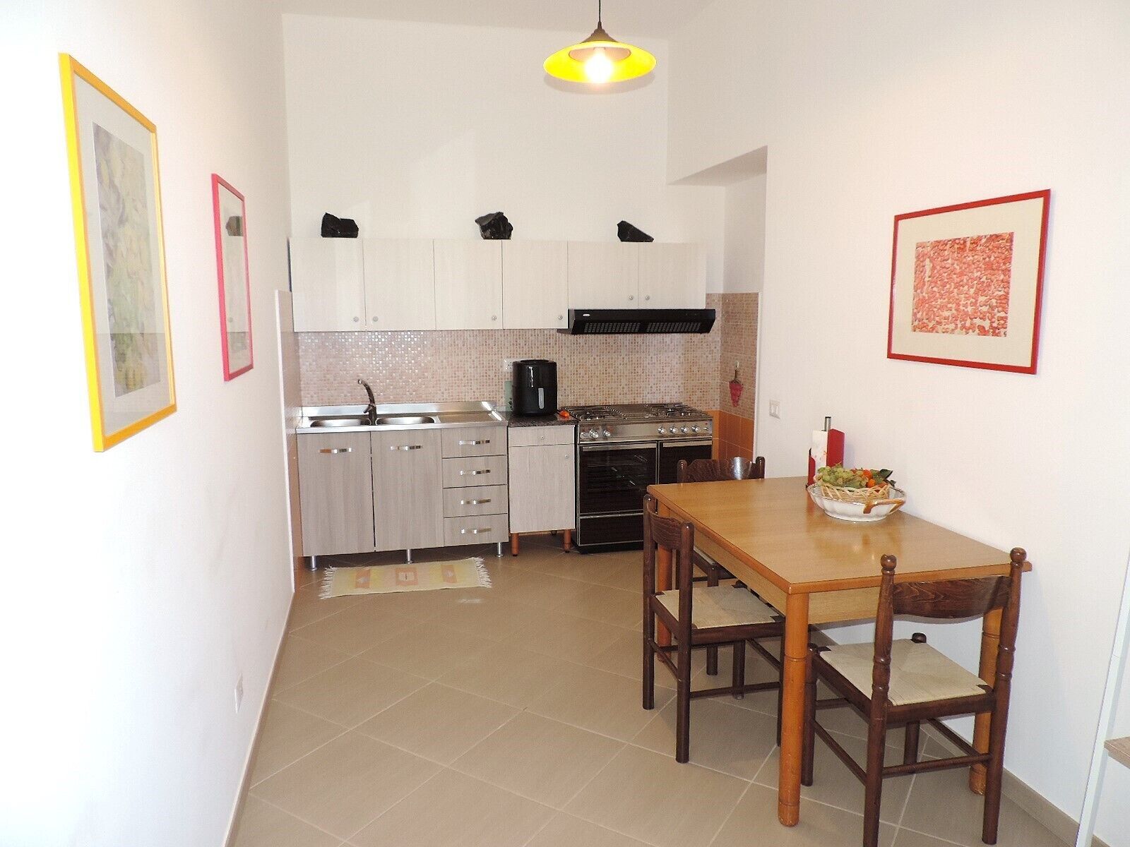 A compact kitchen with a dining area, featuring cabinets, a stove, and a sink.