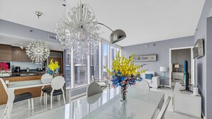 A modern kitchen with a dining area, large windows, and a chandelier.