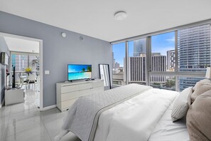 Un dormitorio moderno con una cama grande, televisión y vistas a la ciudad.