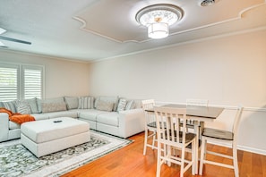 A living room with a sectional sofa, a dining table with chairs, and a patterned rug.