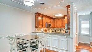 Uma cozinha com armários de madeira, micro-ondas e uma área de refeições com mesa e cadeiras.