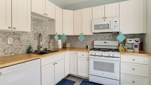 A kitchen with white cabinets, a microwave, a stove, and a dishwasher. - Walk to Beach & Explore Boardwalk: Wildwood Escape (Wildwood)