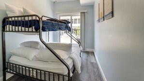 A room with a bunk bed, a ceiling fan, a window with curtains, and a framed picture on the wall. - Walk to Beach & Explore Boardwalk: Wildwood Escape (Wildwood)