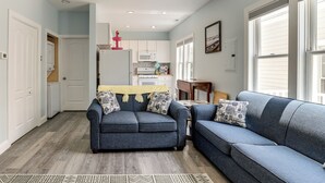A living room with a blue sofa, a coffee table, and a patterned rug. There is a kitchen in the background with white cabinets and a microwave. - Walk to Beach & Explore Boardwalk: Wildwood Escape (Wildwood)