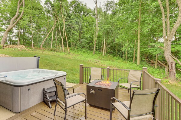 Una terraza con jacuzzi, fogata y mobiliario exterior.