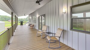 Ein überdachter Außenbereich mit Holzdeck, Schaukelstühlen mit Metallgestell und Deckenventilator.