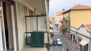 A narrow street with buildings on either side, a green metal structure, and a few pedestrians. - Casa Francy - Taggia (Taggia)