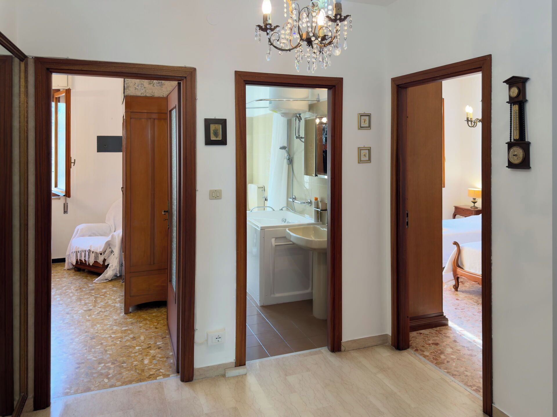 A hotel room with a bathroom, a bed, and a chandelier.