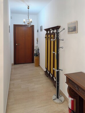 A hallway with a wooden door, a chandelier, a coat rack, and a painting on the wall. - Casa Francy - Taggia (Taggia)