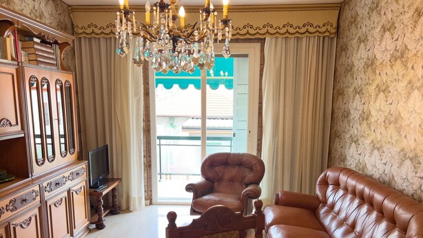 A living room with a brown leather sofa, a wooden chair, a wooden cabinet, and a chandelier. - Casa Francy - Taggia (Taggia)