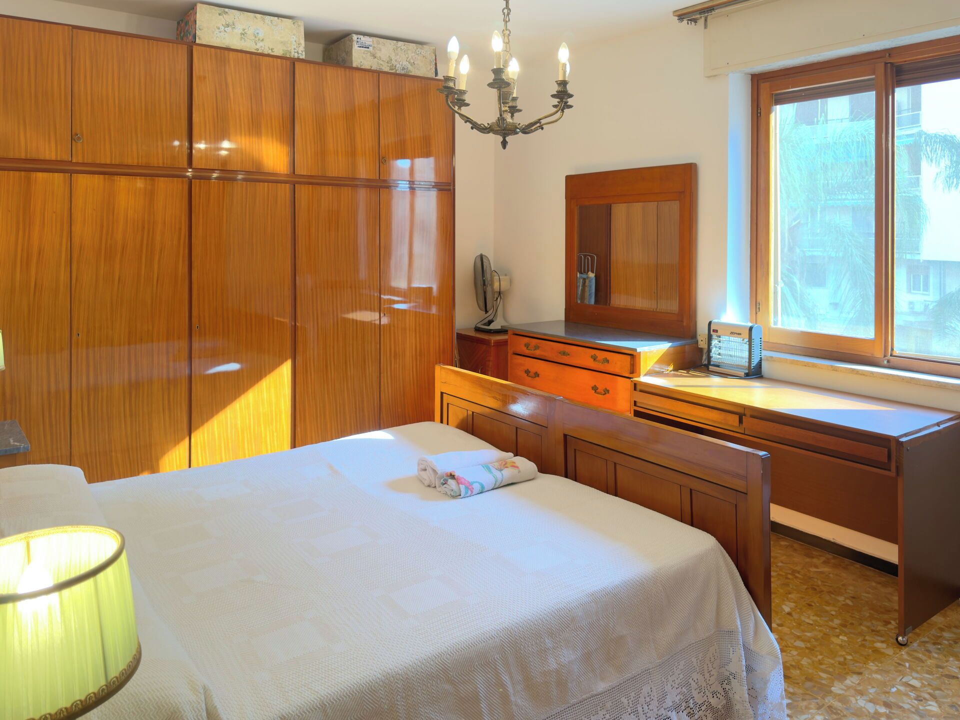Un dormitorio con cama, escritorio, armario, espejo y ventana.