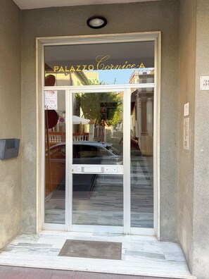 A hotel entrance with a glass door, a sign above the door, and a doormat.