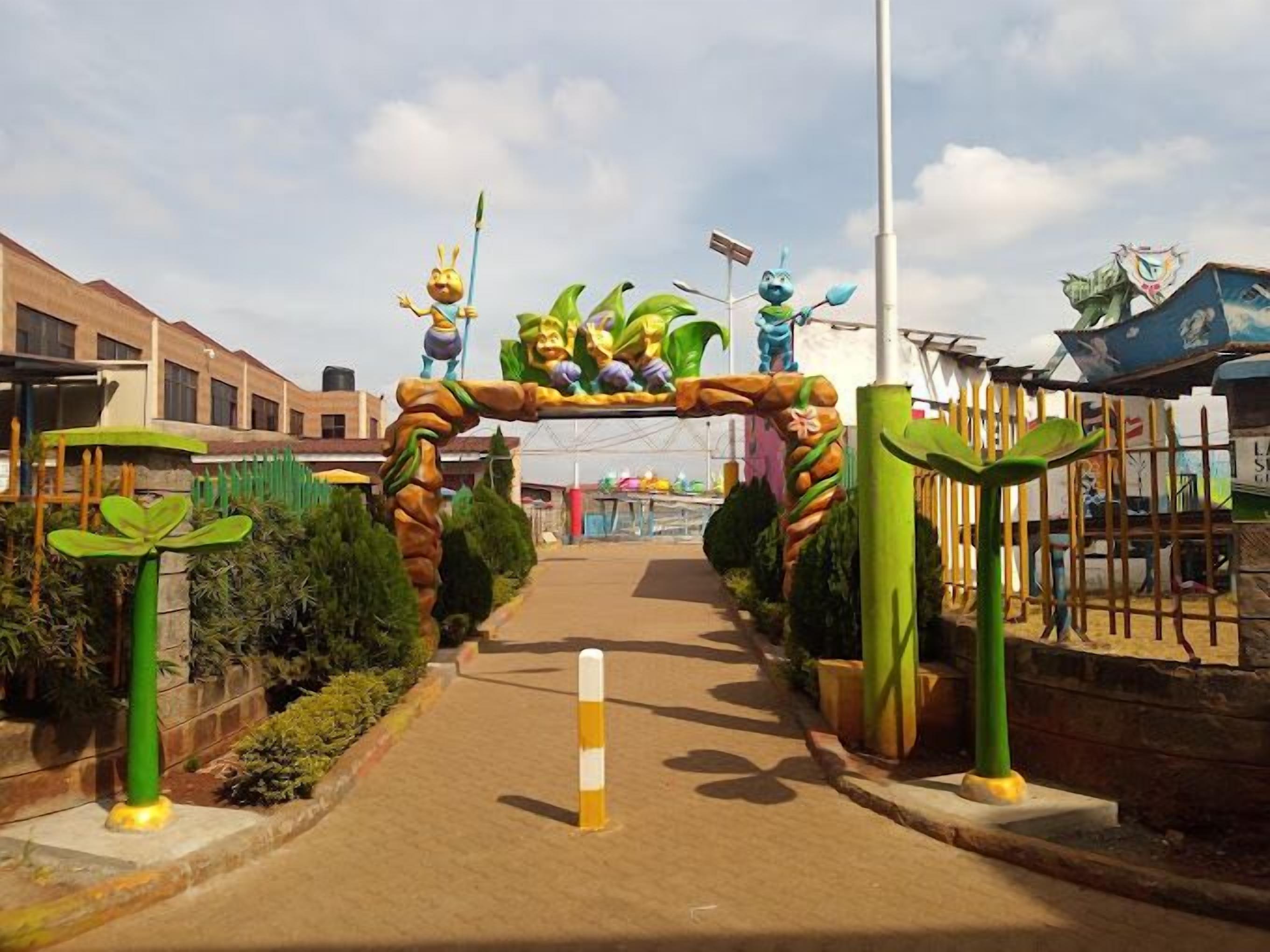 An entrance with a decorative archway featuring cartoonish characters and greenery.