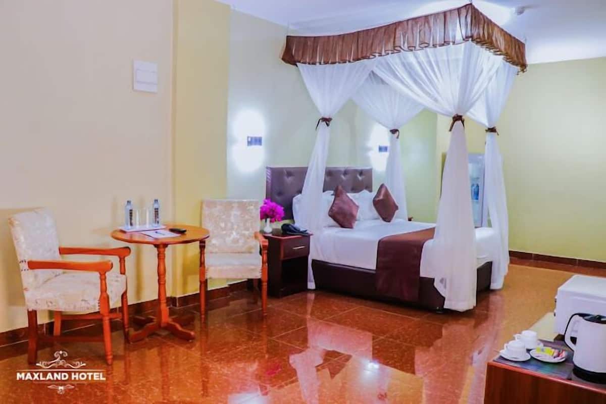 A hotel room with a bed, a chair, a table, and a nightstand.