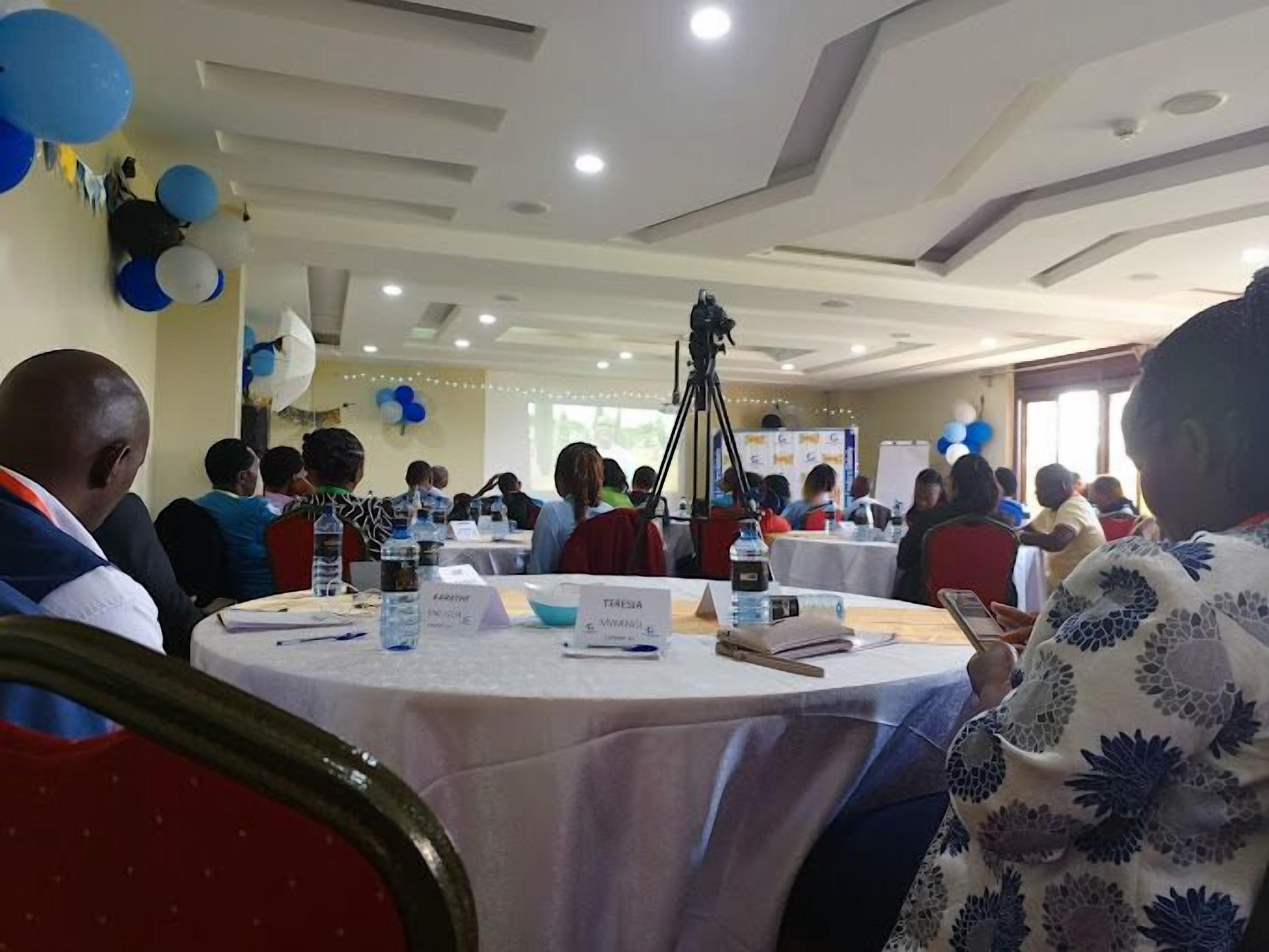 A conference room with round tables, name placards, and a camera on a tripod.