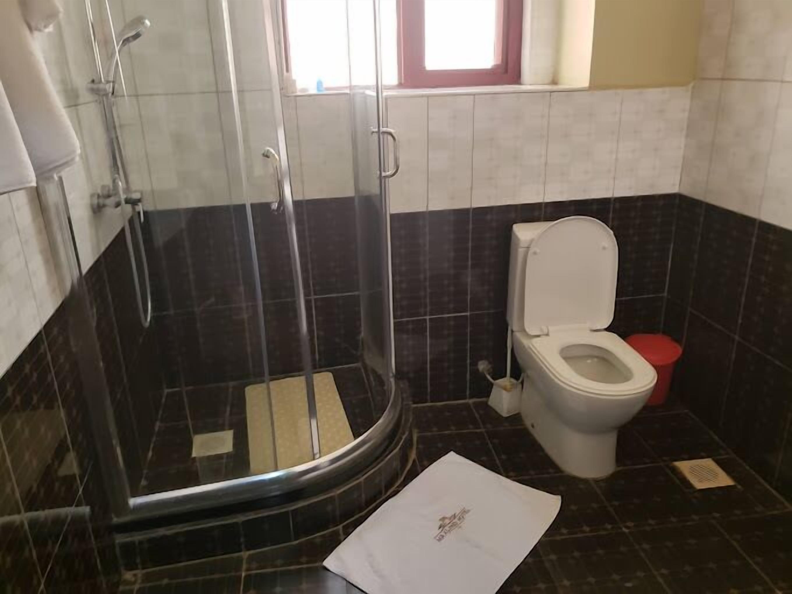 Ein Badezimmer mit einer Duschkabine, einer Toilette und einem Fenster über der Toilette.