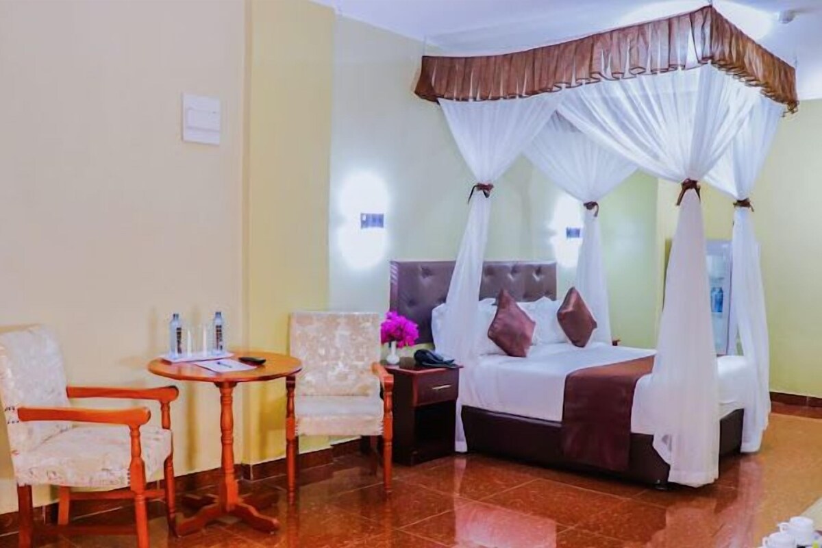 A hotel room with a bed, a chair, a table, and a nightstand.