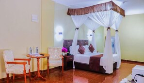 A hotel room with a bed, a chair, a table, and a nightstand. - Maxland Hotel Juja (Juja)