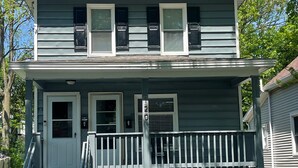 A two-story house with a front porch, a small staircase leading to the entrance, and a mailbox.