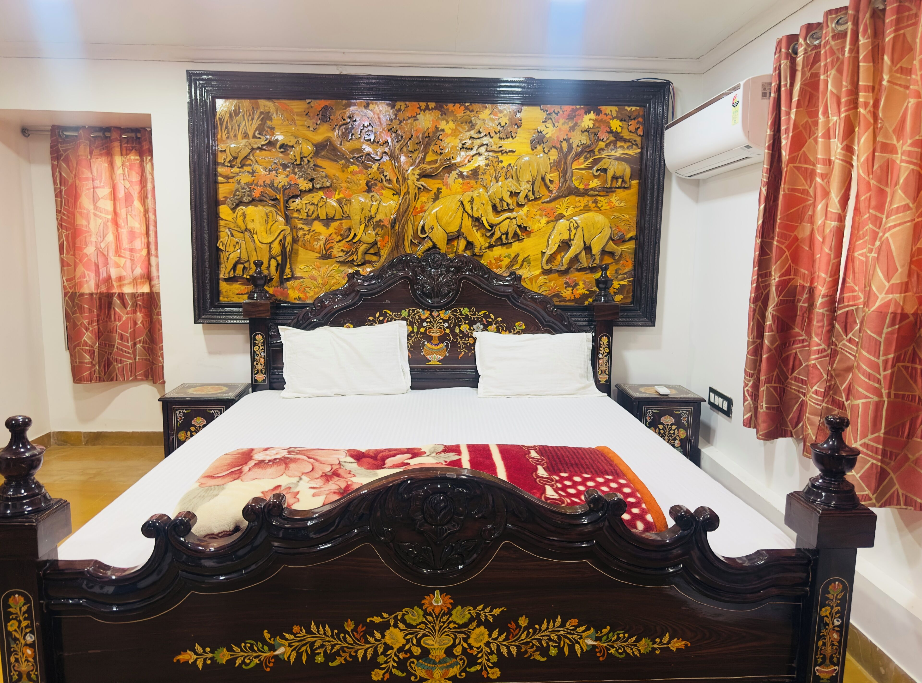 A bedroom with a large bed, ornate headboard, and a vibrant painting above the bed.