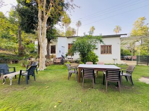 Un espace patio aménagé avec une table et des chaises, entouré de verdure et d’arbres.
