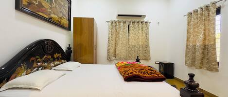 Un dormitorio ordenado con cama, armario, aire acondicionado y cortinas.