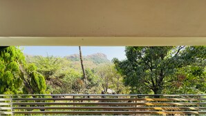 Un balcon offrant une vue sur une végétation luxuriante et des montagnes lointaines.