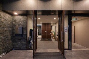 A modern hotel entrance with a glass door, a reception desk, and a wall-mounted sign. - XS06 XROSS STAY Namba3 (大阪市中央区島之内)