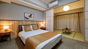 Habitació d'hotel amb un llit gran, un panell de fusta al capçal, dues taules de nit amb llums, aire condicionat fixat a la paret, una obra d'art abstracta emmarcada i una porta corredissa que dona a un bany.