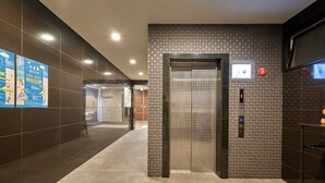 Un ascensor modern amb pantalla digital, envoltat d'un passadís amb parets i terra de rajola.