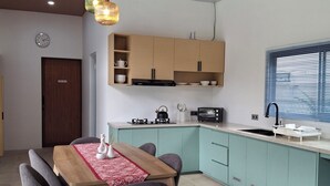 A modern kitchen with teal cabinets, a wooden dining table, and a built-in oven.