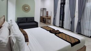 A bedroom with a large bed, a sofa, a desk, and a mirror.
