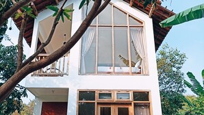 A two-story house with a swimming pool, large windows, and a balcony.