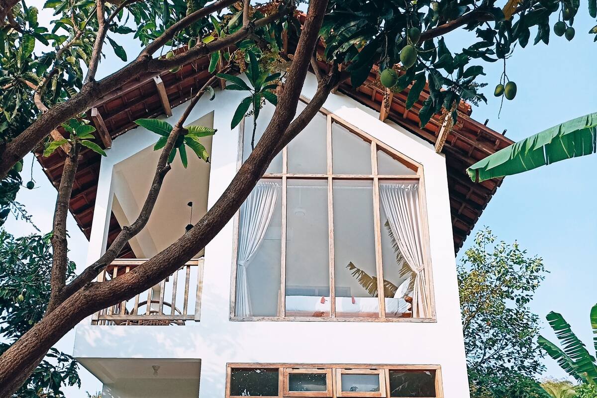Una casa de dos pisos con piscina, ventanas amplias y un balcón.