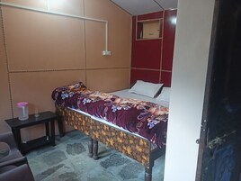 Una habitación pequeña con una cama individual, un edredón estampado con flores, una mesita de noche con lámpara y una pared de acento roja.