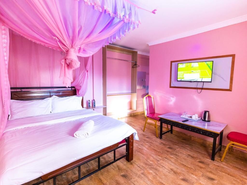 A bedroom with a bed, a TV, a desk, and a chair.