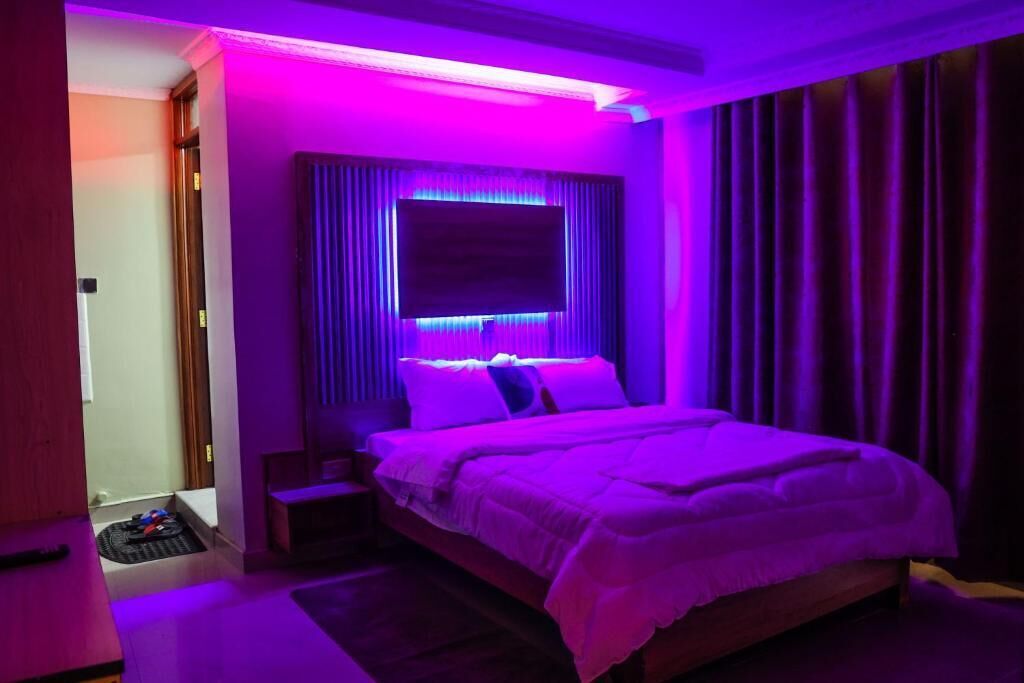 Une chambre à coucher avec un lit, des rideaux et un téléviseur.