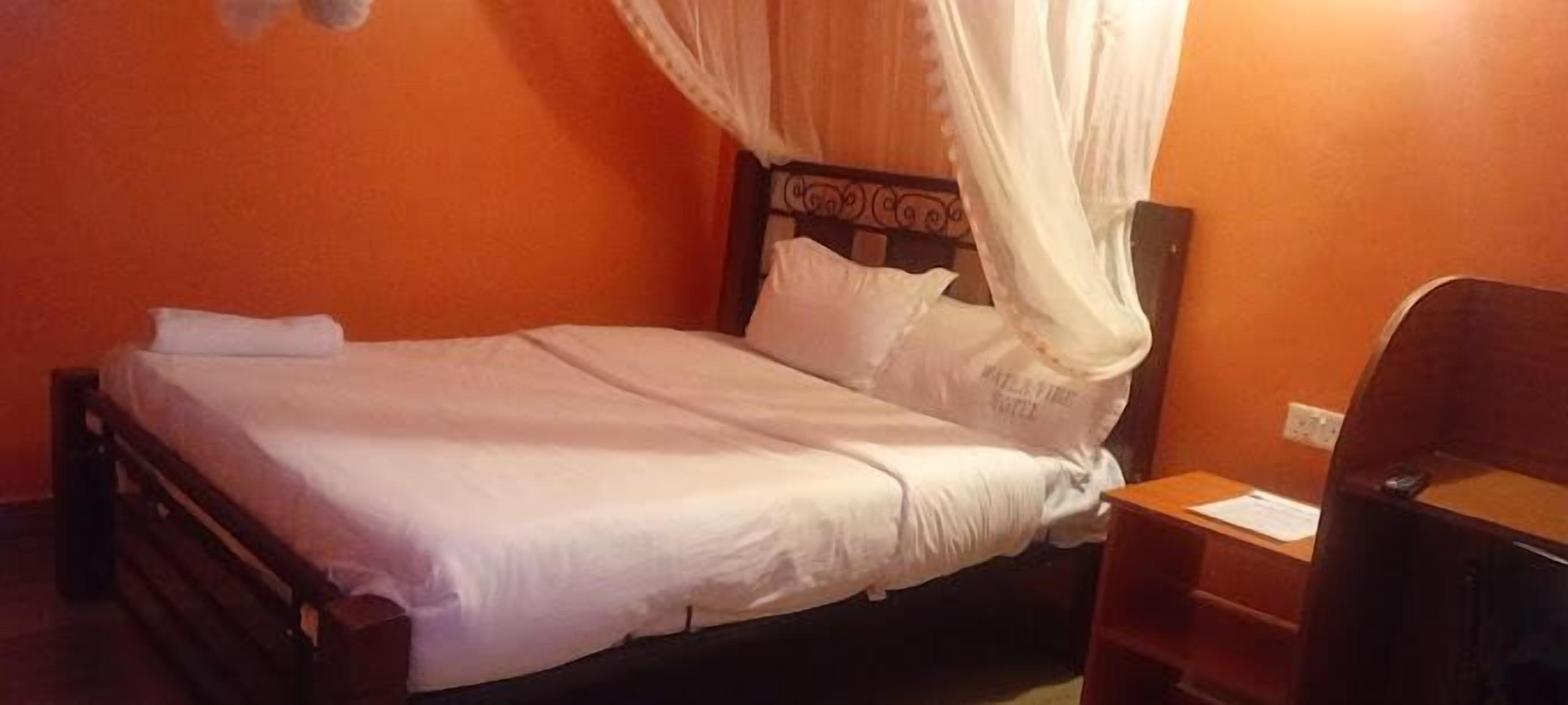 Una cama individual con dosel, una mesita de noche y una mesilla.
