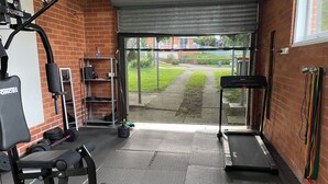 Une salle de sport équipée d’un tapis de course, d’un banc de musculation et de divers appareils d’exercice.