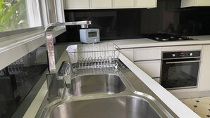 Une cuisine moderne dotée d’éviers en acier inoxydable, d’un grille-pain et d’un four encastré.