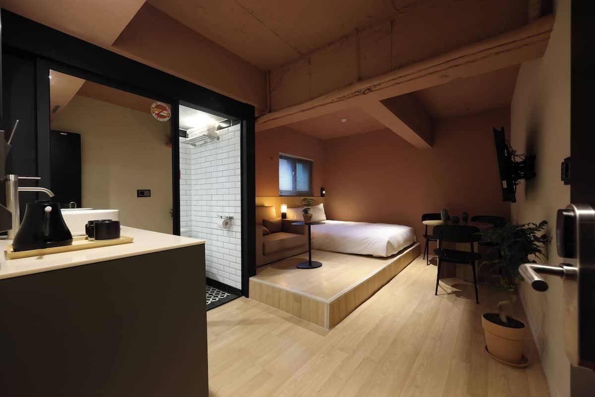 Una habitación pequeña con cama, mesita de noche y un espacio de trabajo.