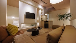 Uma sala de estar moderna com um sofá, uma mesa de centro e uma televisão fixada na parede.