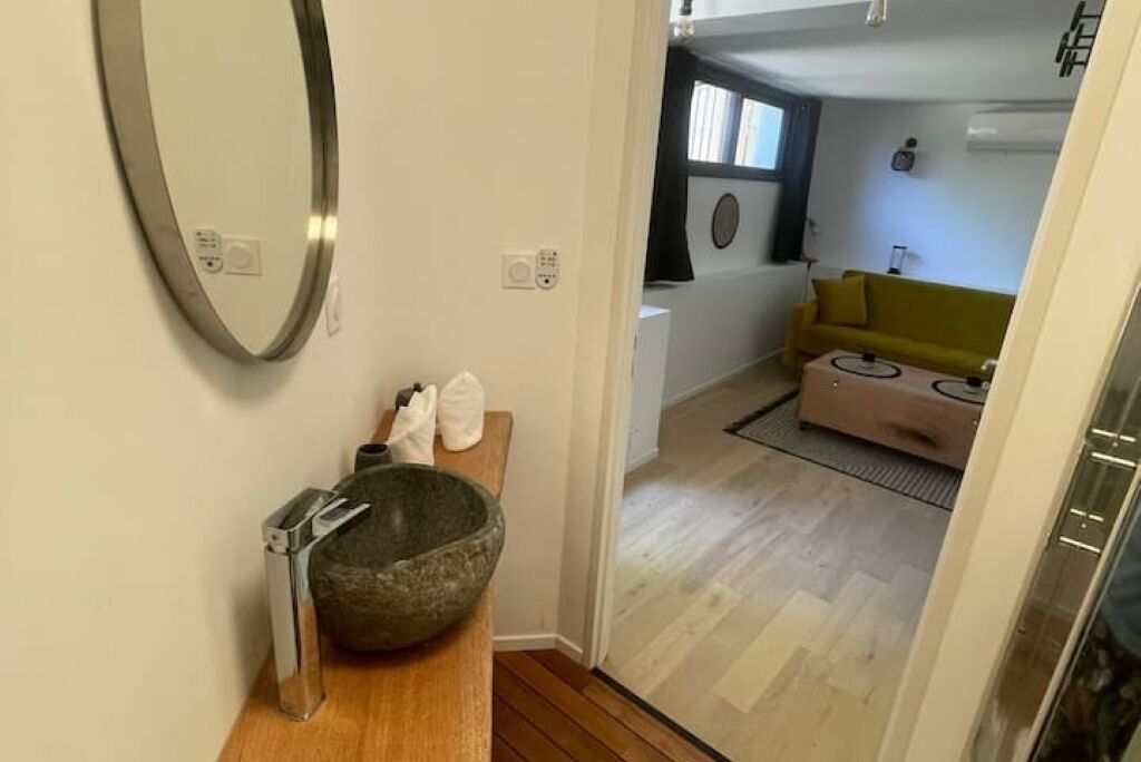 A modern bathroom with a stone basin, a mirror, and a wooden vanity.