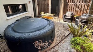 A backyard with a hot tub, a barbecue grill, and a dining area with outdoor furniture. - Cocoon under the oaks with jacuzzi (Saint-Martin-de-Londres)