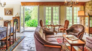Un salon spacieux avec un grand canapé, deux fauteuils, une table à manger et un lustre.