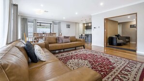 Ein modernes Wohnzimmer mit Ledersofa, einem gemusterten Teppich und einem Essbereich mit Stühlen und Tisch.