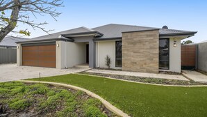 Ein modernes Einfamilienhaus mit Garage, kleinem Vorgarten und gepflegtem Rasen.