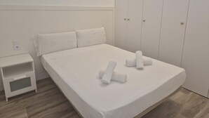 Ein schlicht eingerichtetes Schlafzimmer mit einem Einzelbett, einem Nachttisch und einem Kleiderschrank.